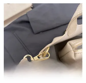 Detail showing the golden swivel hook and precise stitching on beige lychee leather