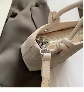 Detail of woven straw bucket bag with beige leather trim and polished silver hardware