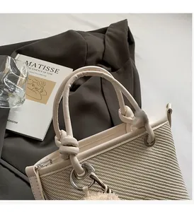 Detail of woven straw bucket bag with knotted leather handle and silver metal rings
