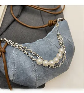 Close-up of light blue washed fabric crescent bag with silver chains and pearl charms
