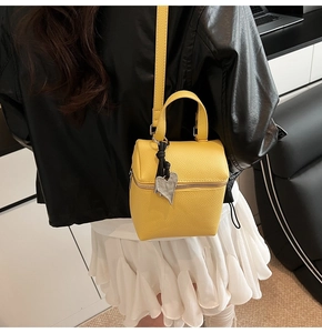 Dettaglio della mini borsa gialla in pelle testurizzata con ciondolo a cuore in argento