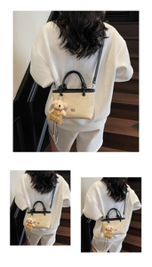 Detail of beige woven bucket bag with black circular handles and bear plush pendant