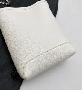 Detailopname van wit leer met lychee-structuur en zilveren ketting van de tas