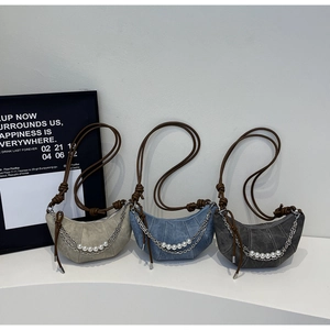 Detailed view of dumpling bags featuring vertical pleats, pearl chains, and rope straps