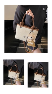 Detail of woven straw bucket bag with brown leather trim and a cute teddy bear charm
