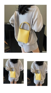 Detail van de felgele crossbody emmertas met litchi-textuur en zilveren ketting