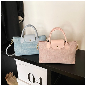 Dettaglio di borse tote in tela intrecciata con manici in pelle e fibbie dorate
