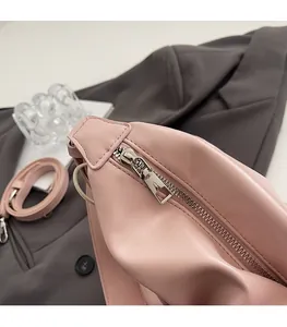 Détail d'une fermeture éclair argentée et d'une bandoulière sur un sac cabas rose en PU