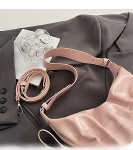 Détail du sac cabas plissé rose clair avec garniture argentée sur un blazer gris