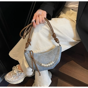 Dettaglio borsa a mezzaluna in denim con catene argento, perle e tracolla con nodo