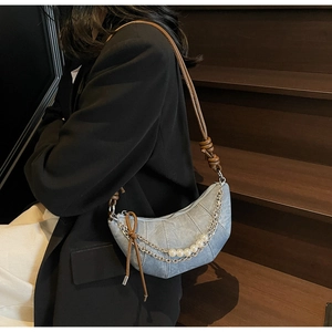 Dettaglio della borsa hobo in denim blu con catena di perle bianche e tracolla in pelle