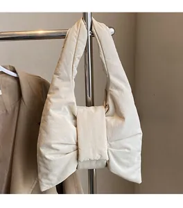 Detail of cream white quilted bow handbag featuring soft padded texture and crossbody strap