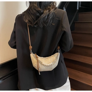 Detail of cream crescent bag with layered pearl and metal chains on a model