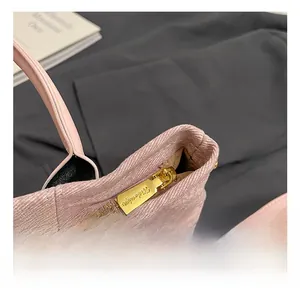 Dettaglio della cerniera dorata su una borsa a mano in tessuto testurizzato rosa