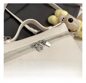 Detail of silver dual zippers and litchi grain texture on white leather handbag