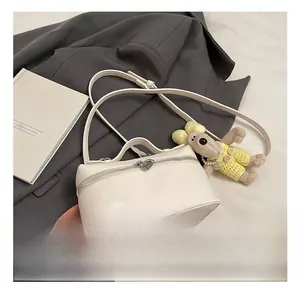 Close-up of white lychee pattern leather bag with heart zipper and plush charm