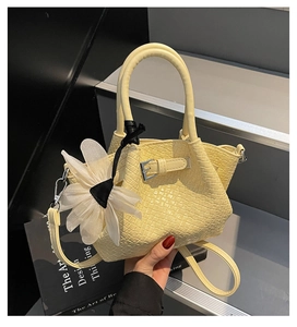 Détail du sac seau tressé avec breloque fleurie et bandoulière réglable amovible