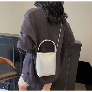 Detail van lichtgrijze crossbodytas van generfd leer met zilveren metalen ketting
