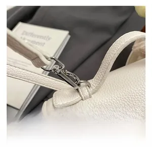 Macro detail of silver metal hook and zipper on white litchi pattern leather handbag