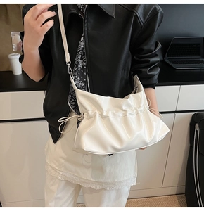 Détail du sac nuage blanc brillant avec design plissé et boucles métalliques argentées