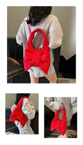 Detail of red oversized bow shoulder bag with padded nylon texture and slim strap
