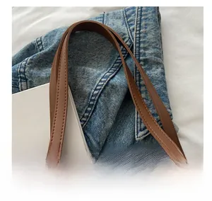 Close-up of brown leather tote bag dual handles with reinforced stitching detail