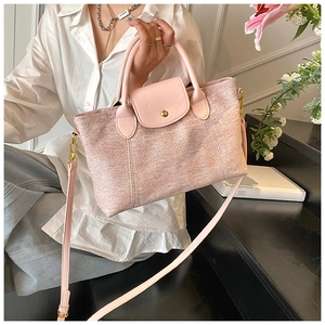 Dettaglio delle finiture in pelle rosa e trama in tela di una grande borsa a tracolla