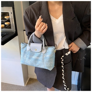 Dettaglio borsa in denim azzurro con patta in pelle grigia e fibbia in metallo argento