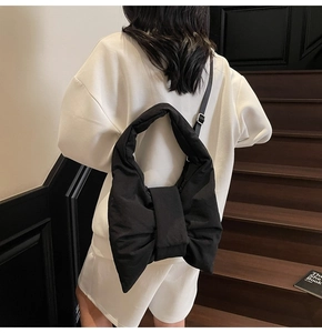 Detail showing the large bow-shaped black nylon shoulder bag worn by a model