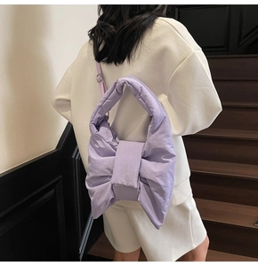 Detail of lavender purple bow-shaped quilted tote bag worn by a model in a minimalist setting