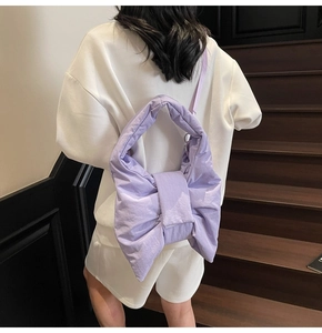 Puffy lavender nylon bow tote bag shown from the back on a white casual outfit