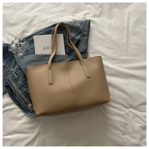 Macro detail of khaki leather tote bag featuring parallel vertical stitching and shoulder straps