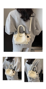 Détail du sac à main crème à texture tissée avec bandoulière et pendentif fleur blanche