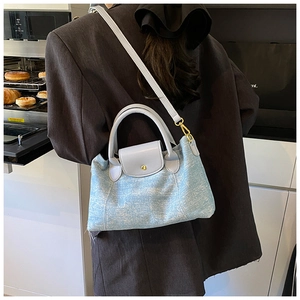 Dettaglio della borsa tote in denim azzurro con manici in pelle grigia e chiusura dorata