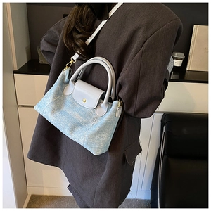Dettaglio della borsa a tracolla azzurra con fibbia dorata su un blazer grigio