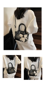 Détails du sac seau noir tressé avec breloque fleur blanche et deux poignées rondes