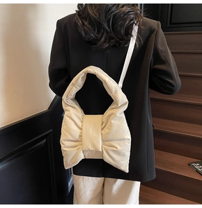 Quilted beige bow tote bag shown on model back view in a wooden staircase setting
