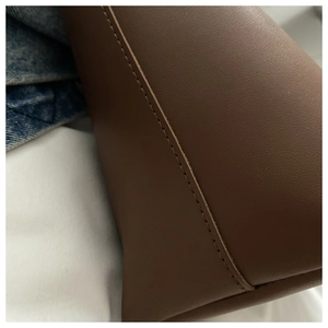 Detailed view of precise stitching on brown faux leather tote bag with matte texture