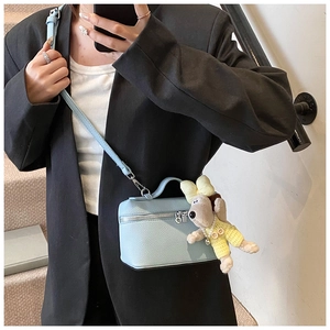 Detail of light blue pebble leather box bag with silver zipper and puppy charm