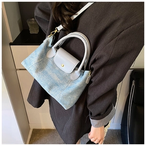 Dettaglio della borsa in denim azzurro con patta in pelle grigia e bottone d'oro