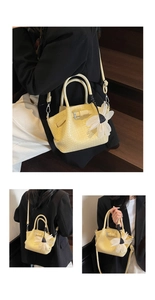 Détail d'un sac seau tressé avec un grand pendentif fleur en mesh et bandoulière réglable