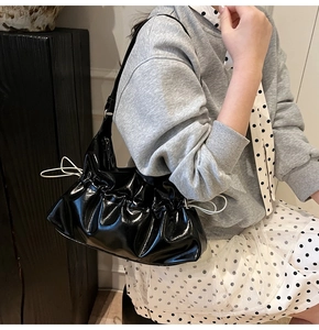 Détail du sac nuage plissé noir avec cordons blancs et texture brillante laquée