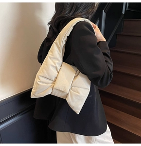 Detail view of the cream quilted bow shoulder bag showing soft texture and wide strap