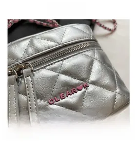 Dettaglio borsa trapuntata argento con logo CLEAR rosa e tracolla a catena