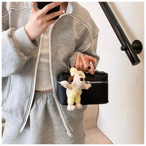 Close-up of black lychee leather handbag with silver zipper and a cute puppy plush charm