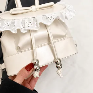 Detail of a white ballet-style leather backpack featuring lace edges and bow decoration