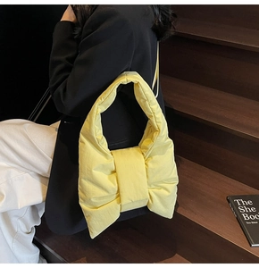 Close-up of a pale yellow bow-shaped nylon tote bag on a model in a casual setting