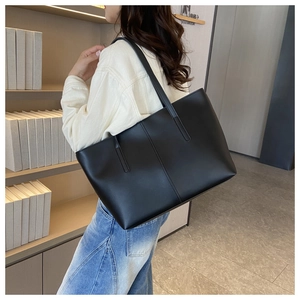 Classic black tote bag with vertical seams shown in a stylish library setting for women