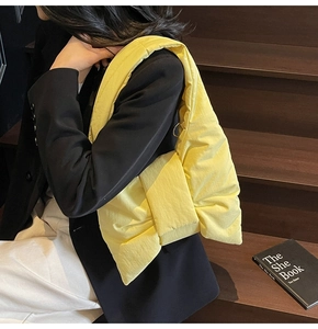 Close-up of bright yellow puffer shoulder bag with metal ring buckle and bow design