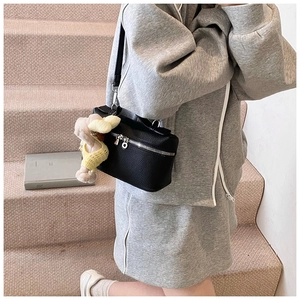 Close-up of black lychee grain leather crossbody bag with a cute knit lamb charm